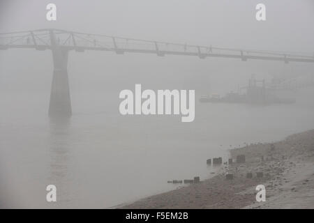 Brouillard matinal enveloppes piétons traversant la Tamise sur le pont du Millénaire. Banque D'Images