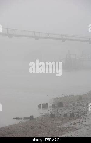 Brouillard matinal enveloppes piétons traversant la Tamise sur le pont du Millénaire. Banque D'Images