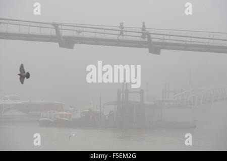 Brouillard matinal enveloppes piétons traversant la Tamise sur le pont du Millénaire. Banque D'Images