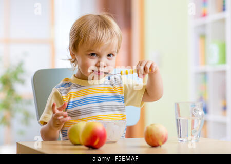 Heureux l'enfant de manger des aliments fromage avec fruits à la maison Banque D'Images