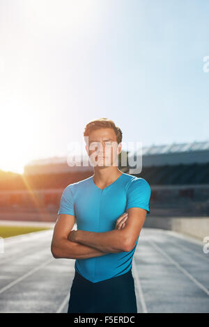 Athlète professionnel hommes debout avec les bras croisés en regardant la caméra. Runner standing in Lane à la piste d'athlétisme Banque D'Images