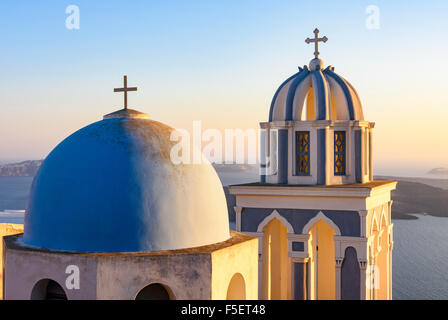 Coucher de soleil sur une église au dôme bleu sur l'île de Santorini, Cyclades, Grèce Banque D'Images