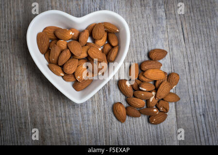 Les amandes dans un bol en forme de coeur Banque D'Images