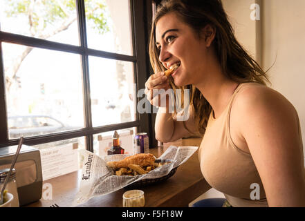 Young Caucasian woman Eating fish and chips dans un restaurant. Banque D'Images