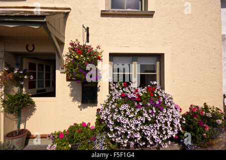 Les jardinières suspendues et panier rempli de fleurs aux couleurs vives sur une maison à Polperro Cornwall UK Banque D'Images