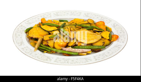 Chips de légumes séchés sur un vieux plat de service ovale isolé sur un fond blanc. Banque D'Images