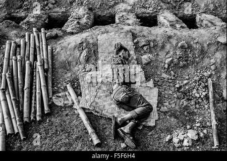 1 mai 2013 - Savar, Dhaka, Bangladesh - un homme dort à côté de la tombe avant l'enterrement de masse des trous de victimes non identifiées à..Jurain cimetière. Le 24 avril 2013, un édifice de huit étages s'est effondré à Savar, près de la capitale du Bangladesh Dhaka, tuant plus de 1 100 personnes environ 2 500 blessés. Le Rana Plaza, qui abritait cinq usines de vêtements, avait été conçu avec seulement six histoires et destinées à des boutiques et des bureaux seulement. (Crédit Image : © Rahul Talukder via Zuma sur le fil) Banque D'Images