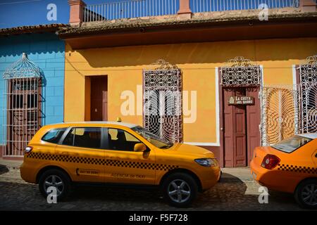 Les taxis jaune garée dans une rue pavée avec des maisons colorées à Trinidad Cuba Banque D'Images