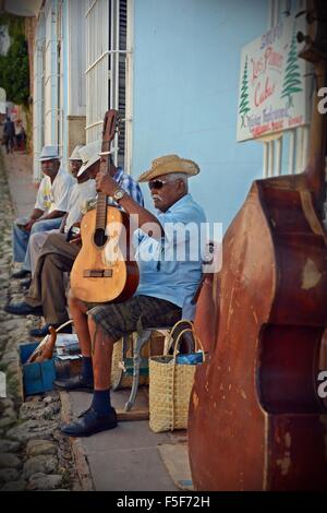 Concert cubain et prendre une pause assis sur le côté d'une rue pavée, à Trinité portant des chapeaux de paille avec une contrebasse, guitare Banque D'Images