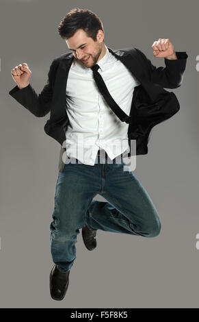 Young businessman jumping joyeuse sur fond gris isolé Banque D'Images