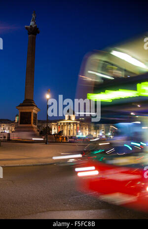 Trafalgar Square la Colonne Nelson et de la National Gallery de nuit avec London bus rouge passant par with motion blur Banque D'Images