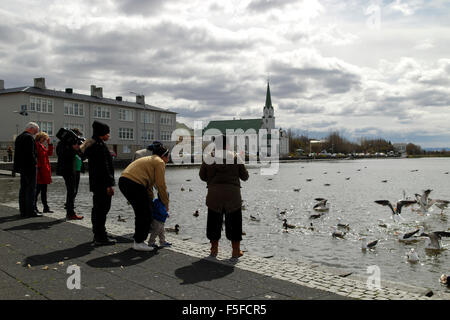 Famille à nourrir les canards du Lac Tjörnin Islande Reykjavik Banque D'Images