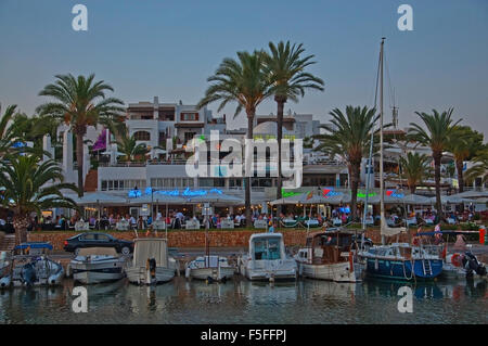 Belle marina avec de petits bateaux et de néons colorés reflétée dans l'eau au crépuscule Banque D'Images