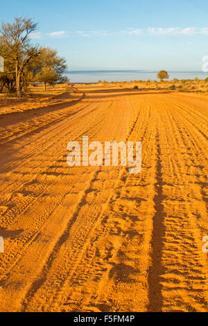 Et rugueux de sable ondulé route de terre qui s'étend à l'horizon lointain sous ciel bleu & menant à Australian Outback ville de Innamincka Banque D'Images