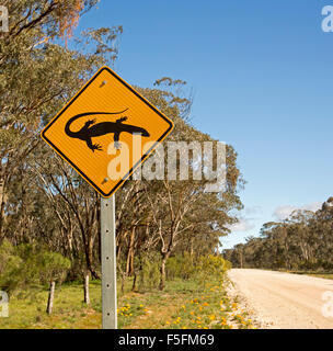 Avertissement signe de présence de lézards goannas, passage à niveau, route de gravier à travers des bois dans la région rurale du sud de l'Australie Banque D'Images