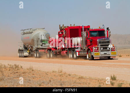 Road train, semi-remorque rouge énorme / camion chargé de l'équipement minier avant de nuage de poussière sur la route de l'outback australien Banque D'Images