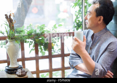 Mature man drinking tea in salon de thé Banque D'Images