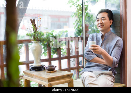 Mature man drinking tea in salon de thé Banque D'Images