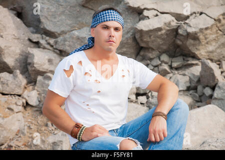 Belle homme assis sur un rocher dans les montagnes Banque D'Images