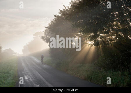 Un cycliste solitaire équitation à travers la brume matinale dans le Yorkshire du Nord. Banque D'Images