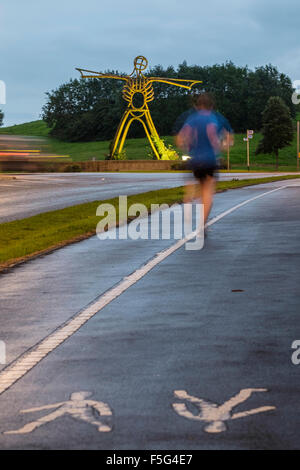 Jogger passé en courant l'homme Vert l'installation de l'oeuvre à proximité de Buckshaw Village de Lancashire Banque D'Images