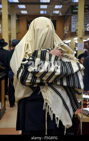 Un homme juif religieux de mettre et sa bénédiction avant de châle de prière matin services à un synaiogue à Brooklyn, New York Banque D'Images