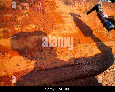 4 novembre 2015 - Dala, Division de Yangon, Myanmar - un travailleur utilise un chalumeau pour brûler des vieux de peinture sur la coque d'un petit traversier en bois sur les rives de la rivière Yangon à Dala. Dala est situé sur la rive sud du fleuve Yangon en face du centre-ville de Yangon, Myanmar. De nombreux Birmans vivent dans Dala et les communautés environnantes et aller de l'autre côté de la rivière dans le centre de Yangon pour travailler. Avant la Seconde Guerre mondiale, l'Irrawaddy Flotilla Company avait ses principaux chantiers de Dala. Cette tradition perdure dans les petites entreprises les travaux de réparation sur les centaines de petits bateaux en bois qui servent de ferries de banlieue pour les gens de Banque D'Images