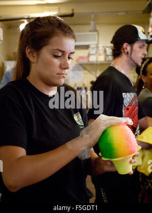 Un travailleur met sur pied un arc-en-ciel Hawaiian shave ice (glace pilée) à raser scandinaves en glace Kailua-Kona, Hawaii. Banque D'Images