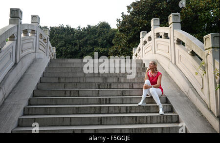 Shanghai, Chine. Août 31, 2015.-dpa exclusif - Maja Synke, princesse de Hohenzollern, est assis sur les marches d'un pont de pierre dans le jardin botanique de Shanghai, Chine, 31 août 2015. La princesse de Hohenzollern a présenté sa collection conçue pour les chiens, chats et petits animaux pour animal de jojo à l'étiquette Trixie 'Pet Fair Asia' au cours de sa visite dans la région métropolitaine de Shanghai dans l'est de la Chine. Photo : Jens Kalaene/dpa/Alamy Live News Banque D'Images