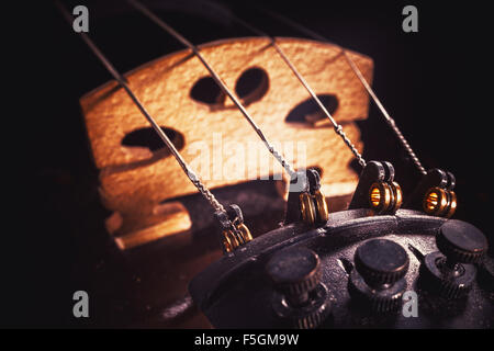 Vue rapprochée d'un ancien violon, détails de cordes, fine tuners et pont. Banque D'Images
