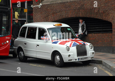 London, UK, 20/10/2015, pilote doit attendre à l'extérieur de son taxi noir avec motif drapeau union pour la course jusqu'à Clapham Junction Station. Banque D'Images