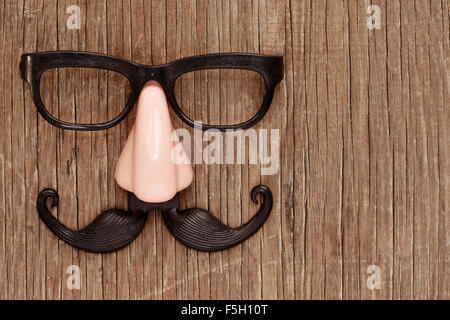 Une fausse moustache, nez et lunettes sur une surface en bois rustique Banque D'Images