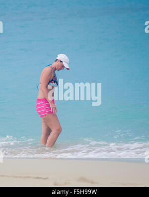 Une femme de race blanche dans un maillot deux pièces patauge dans la mer des Caraïbes. Banque D'Images