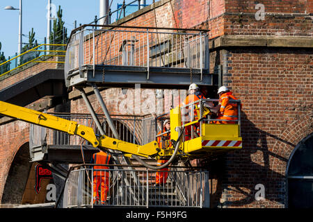 Workman sur une plate-forme d'accès le démantèlement d'un escalier ancien à l'arrêt de tramway le Deansgate-Castlefield, Manchester, Angleterre, RU Banque D'Images