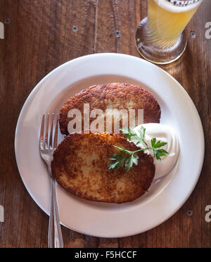 Regardant vers le bas sur une plaque avec deux latkes et de pommes de terre à la crème sure et la bière Banque D'Images