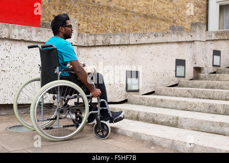 Jeune homme dans un fauteuil roulant au bas d'étapes Banque D'Images