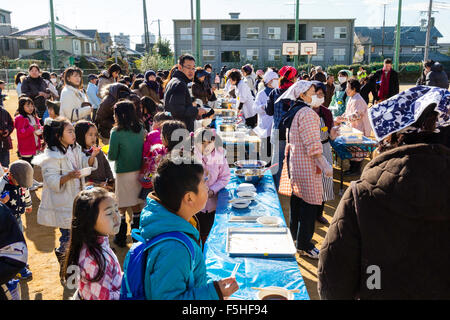 Le Japon. Omochi, riz d'hiver festival tenu à dénigrer l'école locale. Dans les tableaux de jeu, mis en place avec des lignes de personnes queuing pour o-gâteaux de riz mochi. Banque D'Images