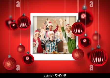 Image composite de extended family in santa hat cheering at camera Banque D'Images