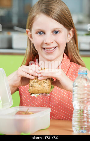 Femme élève assis à table dans la cafétéria de l'École d'une alimentation saine des paniers-repas. Banque D'Images