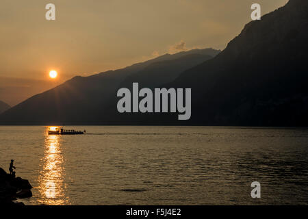 Pêcheur autrichien, voile et montagne silhouette dans un coucher de soleil Banque D'Images