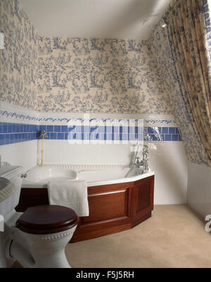 Toile-de-Jouy au-dessus d'une baignoire d'angle avec un panneau d'acajou dans une salle de bains 90 Banque D'Images