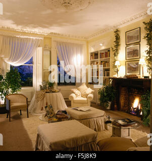 Rideaux voile blanc sur windows dans années 80 appartement salle de séjour avec cheminée à feu lumineux Banque D'Images