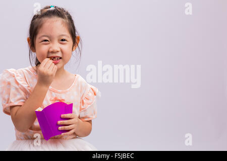 Petite fille est en train de manger des frites avec bonheur. Banque D'Images