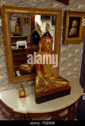 Statue asiatique doré recouvert de marbre sur une table console dans un hall des années 60 Banque D'Images