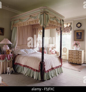 Le vert pâle et rose rideaux sur un lit à baldaquin vert pâle avec valence dans une élégante chambre à coucher années 80 Banque D'Images