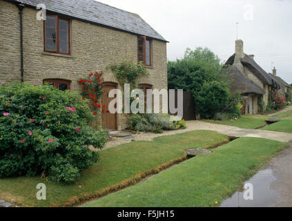 Petit ruisseau en face de cottage récemment rénové avec un Rugosa rose sur la pelouse Banque D'Images