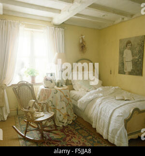 Rocking chair en jaune pâle 80 chambre avec draps blanc peint sur un lit simple Banque D'Images