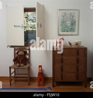 Artisanat Arts +-poitrine de tiroirs dans une chambre avec bain à dossier en dessous de fenêtre avec des volets blancs simples Banque D'Images