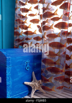 Close-up d'une petite armoire peinte en bleu à motifs de poissons et de rideau de douche en plastique Banque D'Images