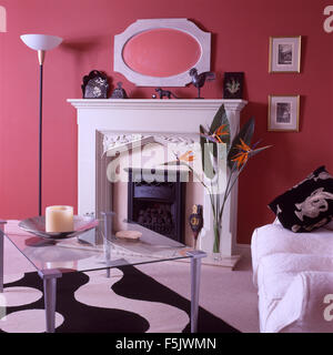 Table basse en verre noir et blanc +tapis à motifs abstraits dans un rose lumineux 90 salon avec une cheminée et canapé blanc Banque D'Images